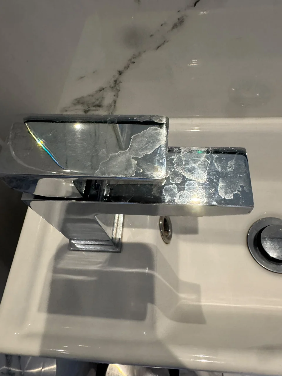 Bathroom tap and basin before cleaning, with visible surface residue